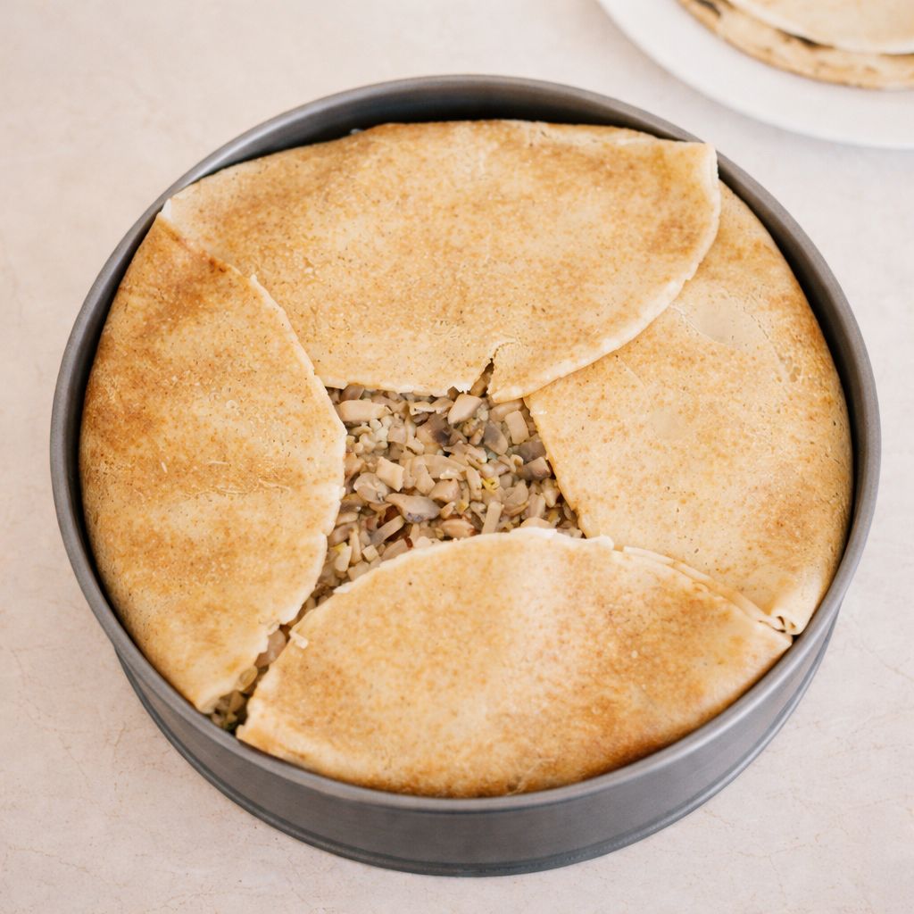 Układanie ostatniej warstwy naleśników w daniu à la rosyjski Kurnik – tortownica z warstwowym nadzieniem z kurczaka, ryżu i pieczarek.