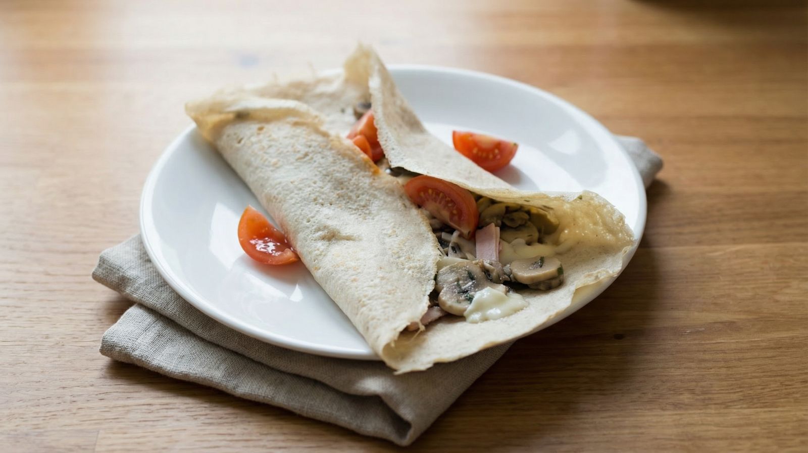 Galettes z szynką i pieczarkami z serem ementaler i pomidorkami koktajlowymi – francuski naleśnik z mąki gryczanej.