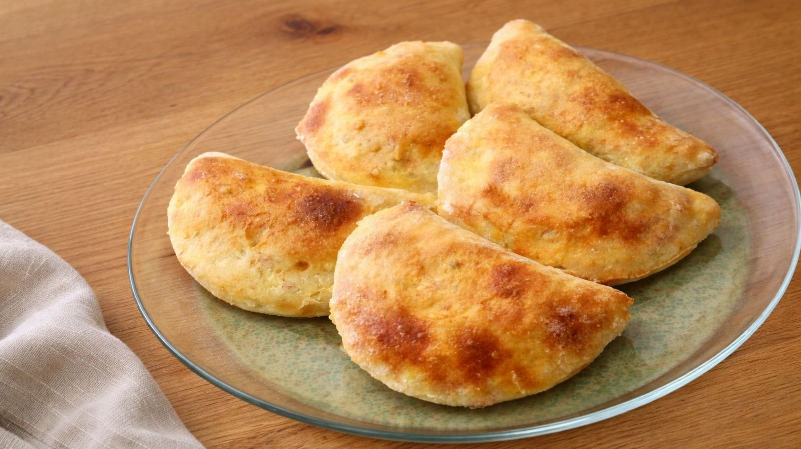 Pieczone pierogi ziemniaczane z kaszą gryczaną na talerzu po wyjęciu z piekarnika.