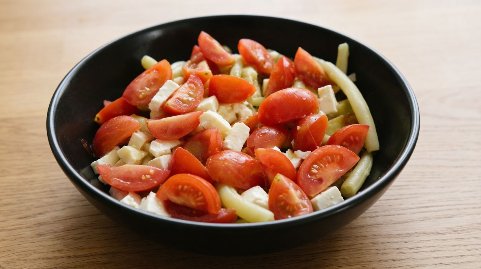 Sałatka z fasolki szparagowej z fetą i pomidorkami koktajlowymi w misce.