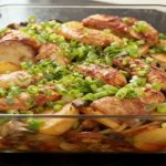 Zapiekane ziemniaki z pieczarkami i kurczakiem w szklanym naczyniu żaroodpornym, posypane świeżą cebulką dymką.